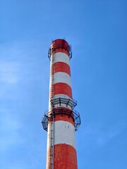A red and white boiler house chimney against a blue sky