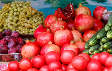 A pile of red fruit including tomatoes, pomegranates, and plums