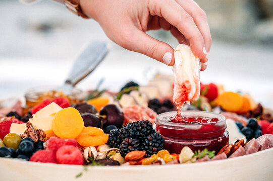 Brie cheese dipped into jam on a vibrant charcuterie board