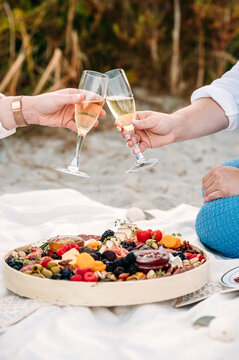 Champagne toast and charcuterie by the beach at sunset