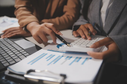 Close up Business woman using calculator and laptop for do math finance on wooden desk, tax, accounting, statistics and analytical research concept