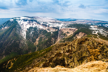 Snow-covered mountain ridges and rocky slopes of Krkonose National Park, Czech Republic, near Snezka peak, scenic panoramic view in springtime.