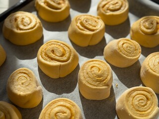 Golden brown cinnamon rolls aligned on a baking sheet, freshly baked and delicious.