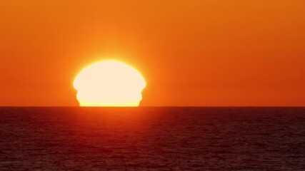 Midnight Sun Over the Sea Waves Close-Up. Sunrise distorted by atmospheric refraction. Lofoten Islands, Northern Norway.