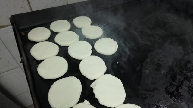 Hot griddle with arepas cooking, creating a tasty and warm feeling