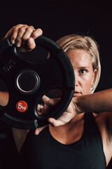 Close-up of a fitness woman holding a weight and looking at the camera, symbolizing strength and...