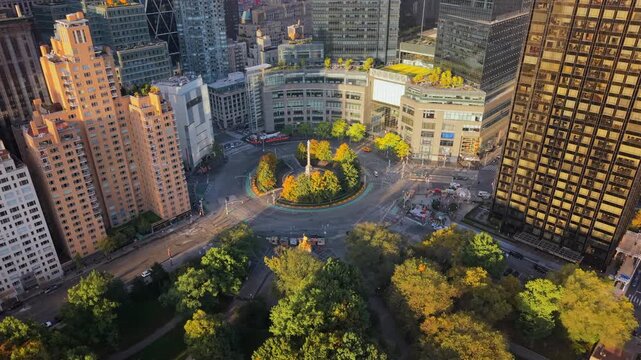 Cinematic Drone shot of Columbus Circle in New York City at golden morning hour, colorful fall trees surrounded by high-rise buildings and tree-filled streets. Manhattan New York, USA