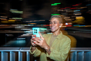 Woman smiling using smartphone capturing city light trails