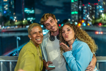 Diverse group of friends taking selfie at night city
