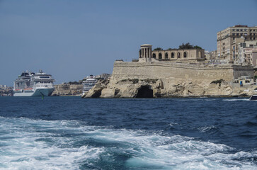 Massive mega Italian family cruiseship cruise ship Grandiosa, Bellissima Meraviglia in Valletta during Summer Mediterranean cruising in sleek modern design with port infrasctructure and marine traffic