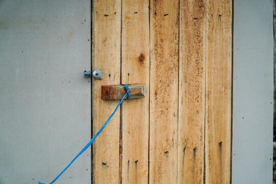 Rustic latch detail showcases a handmade wooden door. The simple closure and aged wood texture evoke a sense of authenticity and charm, capturing a basic structure and design ingenuity.