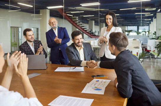 Handshake of business agreement, success contract signing on team meeting in office boardroom. Colleagues shake hands after chart presentation and deal, success interview, corporate teamwork