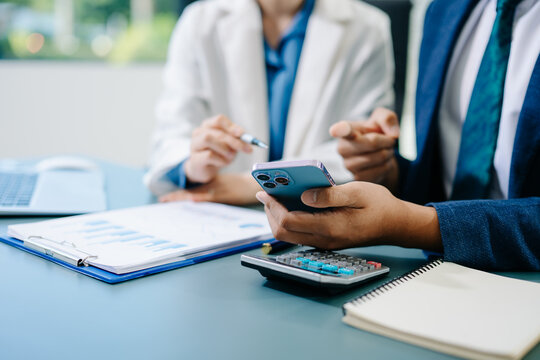 Business documents on office table with smart phone and calculator digital tablet and graph business with social network diagram and two colleagues discussing data - Powered by Adobe