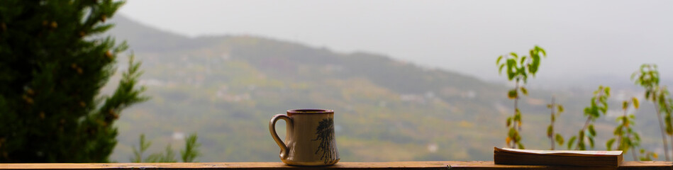 Morning Coffee and Book Reading Against a Misty Mountain View