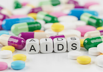 Close up of aids cubes surrounded by colorful pills isolated on white