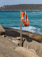 An orange life preserver and rope ready to assist with emergencies off the rocks. Dolphin Cove, Esperance Western Australia.	