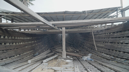 The stern of a traditional Phinisi wooden ship under construction can be seen from inside.