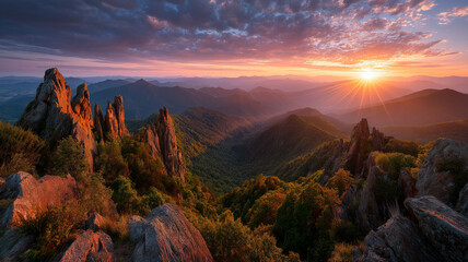 Panoramic mountain vista at sunrise with sun rays and colorful sky