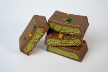 Stack of chocolate bars filled with pistachio cream on white background. Elegant gourmet dessert concept for cafe, packaging, or patisserie branding.