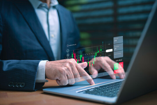 Businessman using laptop with futuristic financial data and stock market graph interface. Concept of digital trading, cryptocurrency investment, and financial technology innovation. - Powered by Adobe