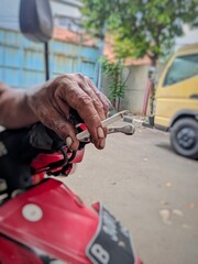 Obraz premium Close-up of Smoker's Hand on Motorcycle Handlebar