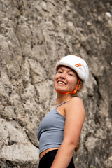 Positive woman rock climber resting after climb outdoors, athlete girl smiling with satisfaction and confidence in mountains