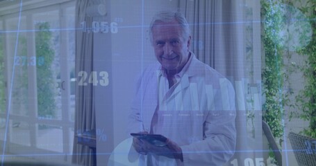 Senior man wearing white lab coat holding tablet reviewing digital chart overlays in modern office