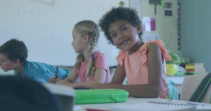 Smiling curly-haired girl in peach top sitting at school desk with green pencil case, copy space - Powered by Adobe