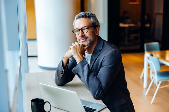 Professional man working on a laptop in a bright open office space - Powered by Adobe