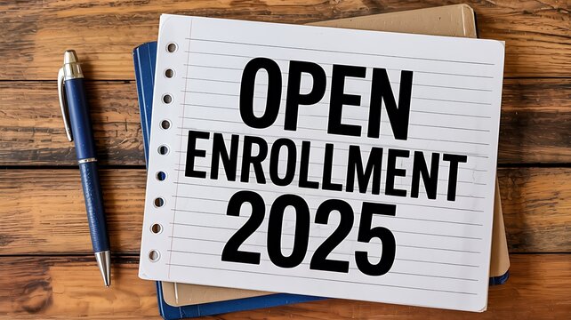 Open enrollment 2025 text written on a notepad with a pen on a wooden desk signifying important deadlines and planning