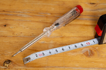 Phase tester and tape measure with signs of wear on a wooden worktop