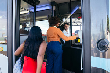 Woman tapping card on payment terminal while boarding a public city bus, with other passengers in the background © Koldo_Studio