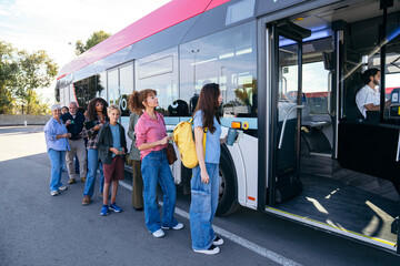 Commuters of various ages and backgrounds waiting in line to board a modern public transport bus at a city bus stop