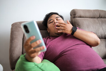 Hilarious Sleepy Guy Yawns While Scrolling on His Phone at Home on Couch