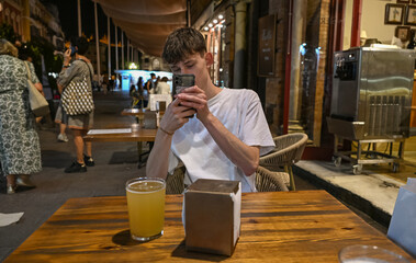 young man taking a photo of his drink in a bar in Sevilla