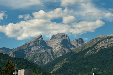 Obraz premium Majestic rocky mountains against a vibrant blue sky dotted with white clouds.