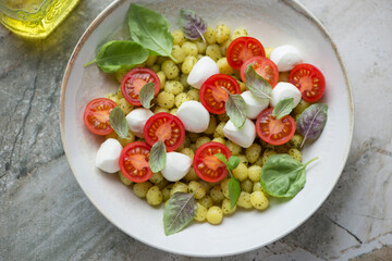 Beige plate with italian chicche di patate served in caprese style, horizontal shot, middle close-up, elevated view