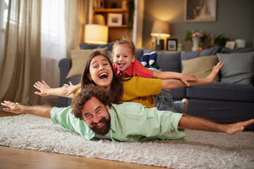Family members enjoy quality time together at home, engaging in a playful activity on the living room floor, filled with smiles and laughter in a cozy atmosphere.