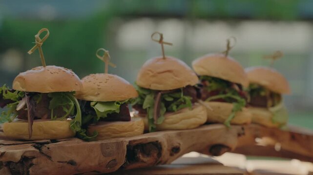 Tempting row of fresh burgers skewered and arranged on natural wood for savory indulgence