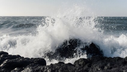 Ocean wave crashing on rocks with white spray.