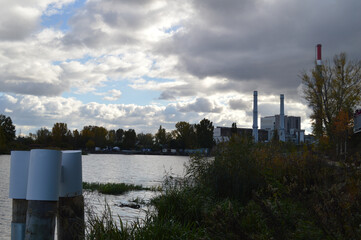 Obraz premium Industrial waterfront with power plant and dramatic cloudy sky - urban industrial landscape