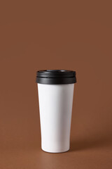 White travel mug with black lid on brown background. Concept of beverage product marketing, lifestyle advertising mockup with simplicity, mobility, and professional rhythm.