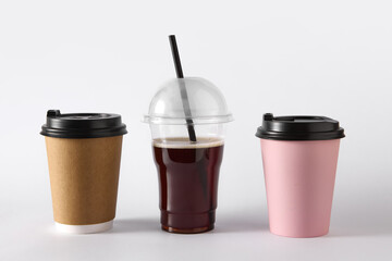 Three takeaway coffee cups with different lids and materials on white background. Concept of packaging design, beverage product mockup, cafe branding for ads and menu visualization.