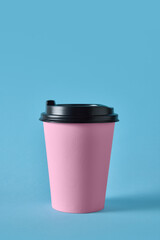 Pink takeaway coffee cup with black lid on blue background for cafe packaging. Concept of beverage branding, packaging design, and mockup advertising for restaurant and catering visuals.