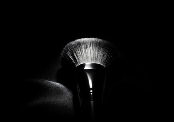 Makeup brush illuminated in dramatic studio lighting with copy space