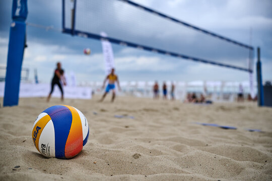 Male athlete holding professional beach volleyball ball on sandy beach with shirtless upper body detail