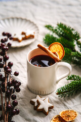 Ein Becher Gl&uuml;hwein mit Orange und Zimtstange auf einem weihnachtlich gedeckten Tisch. Alkoholisches Getr&auml;nk, Advent.