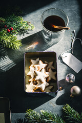 Eine Keksdose mit gebackenen Zimtsternen auf einem weihnachtlich dekorierten Tisch. Draufsicht,...