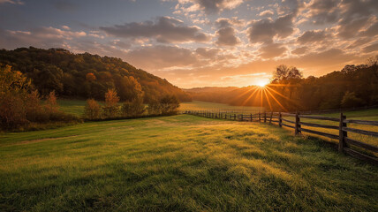 Golden sunrise over a grassy field with a wooden fence and rolling hills