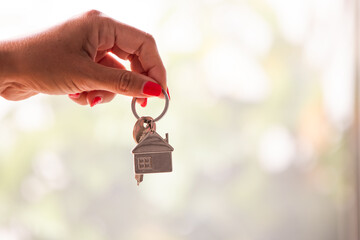 hands with house keychain and keys in blurred background